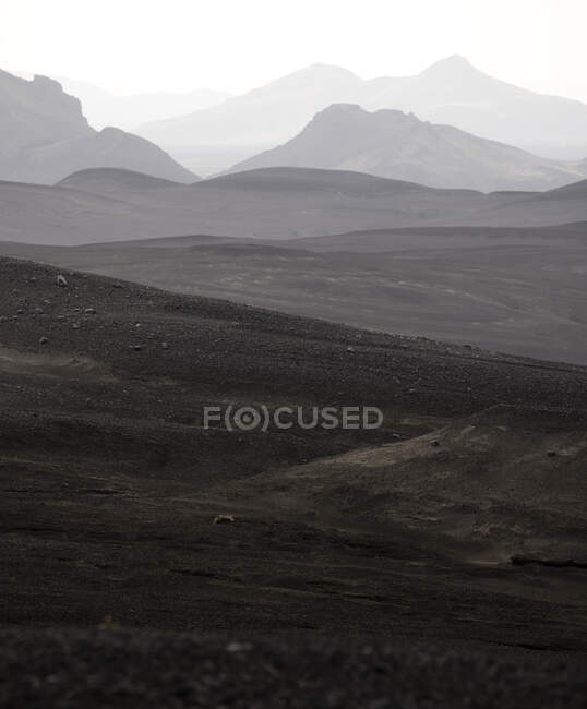 Paesaggio pittoresco di catena montuosa ruvida con cime in nebbia densa sotto cielo cupo in altopiani — Foto stock