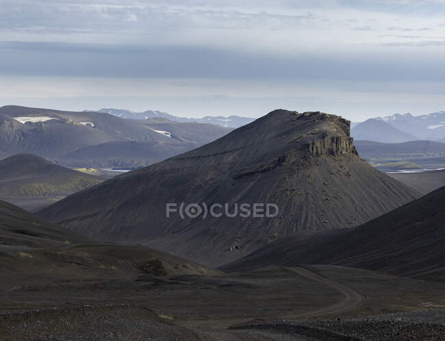 Vista panorámica de formaciones volcánicas rocosas ásperas rodeadas por un valle montañoso seco - foto de stock