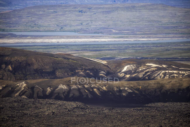 Живописный пейзаж грубого сурового горного хребта, расположенный на холмистой бесплодной долине, покрытой сухой растительностью при дневном свете — стоковое фото