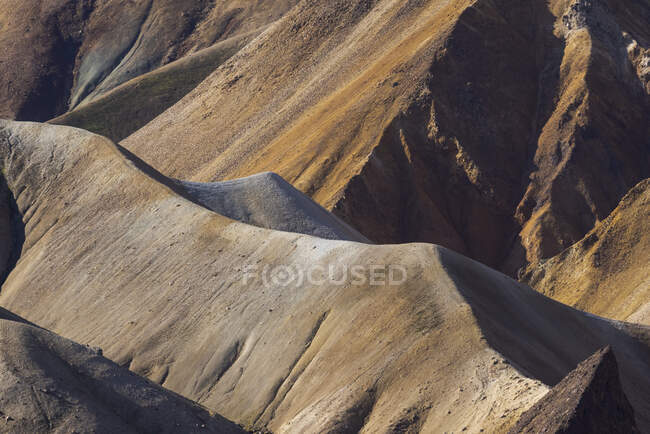 Paisagem espetacular de terreno rochoso sem fim com declives secos e vegetação aleatória localizada sob céu azul claro na Islândia — Fotografia de Stock