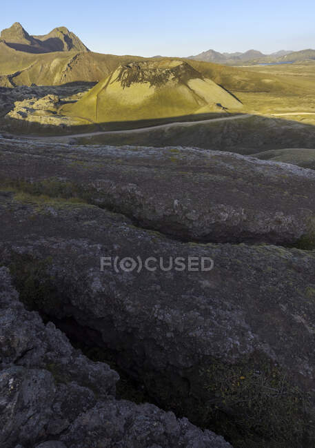 Magnifique paysage de montagnes volcaniques rocheuses avec des sommets éclairés par la lumière du soleil en terrain désertique accidenté en Islande — Photo de stock