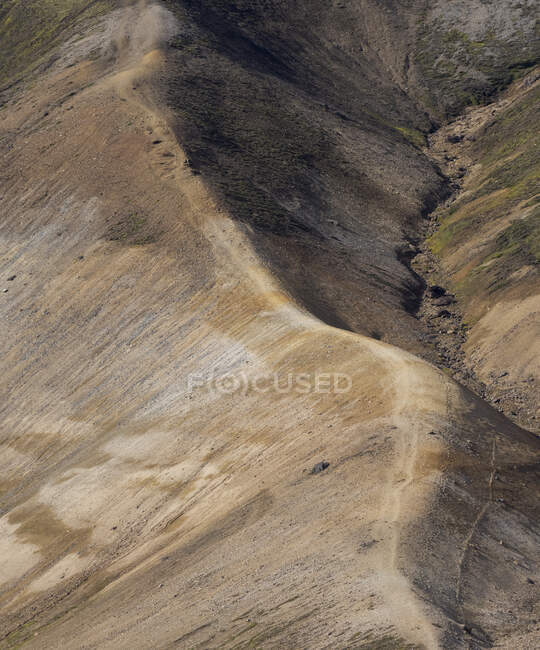 Desde arriba espectacular paisaje de interminable terreno rocoso áspero con pendientes secas y vegetación aleatoria ubicada en Islandia - foto de stock
