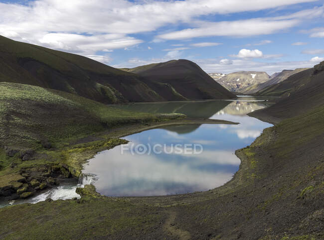 Прекрасный пейзаж холодного кристально чистого озера в окружении грубой горной цепи, покрытой сухой растительностью в ясный день — стоковое фото