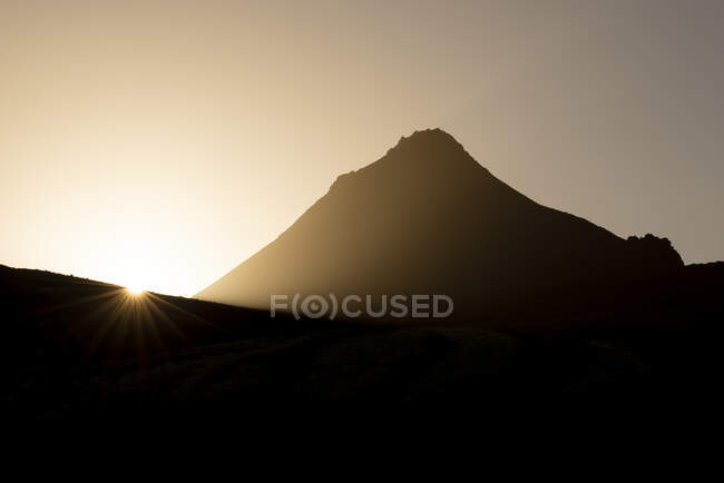 Silhouette pittoresque de montagne rocheuse rugueuse sur les hautes terres spacieuses contre le soleil couchant lumineux dans la soirée paisible — Photo de stock