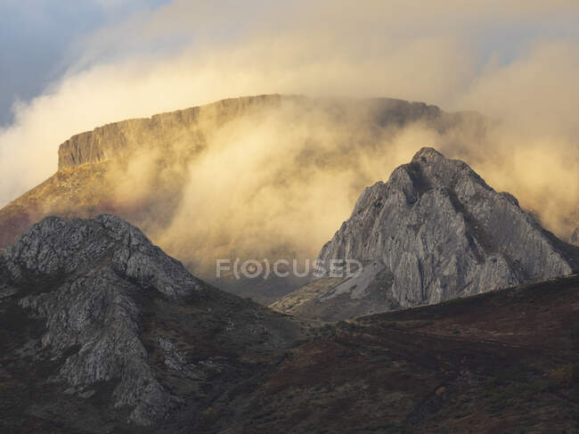 Magnífico paisaje de montañas rocosas con picos iluminados por la luz del sol en terrenos desérticos durante la puesta del sol - foto de stock