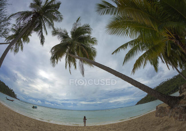 Occhi di pesce persona irriconoscibile in piedi sulla spiaggia di sabbia vicino a palme esotiche e godendo infinito mare azzurro sul tempo limpido e soleggiato — Foto stock