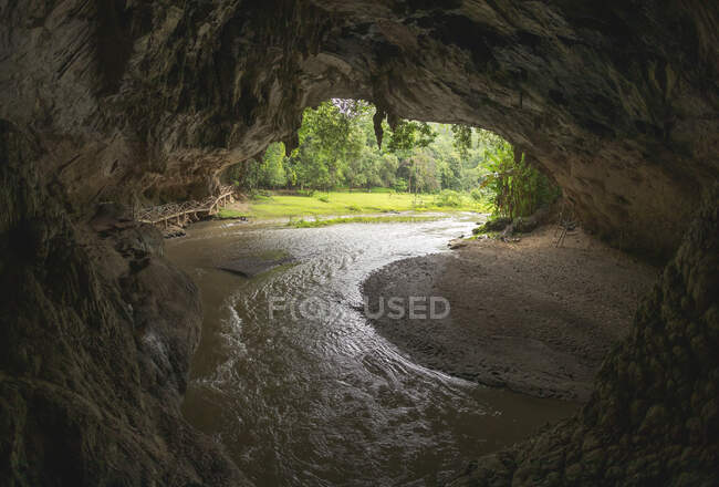 Picturesque scenery of narrow river flowing through Tham Lot cave covered with lush green tropical vegetation in Thailand — Stock Photo