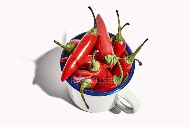 Top view of big ceramic mug full of ripe fresh exotic pepper placed on white background — Stock Photo