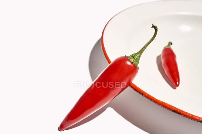 Top view composition of bowl with hot peppers with green stem placed on white background — Stock Photo