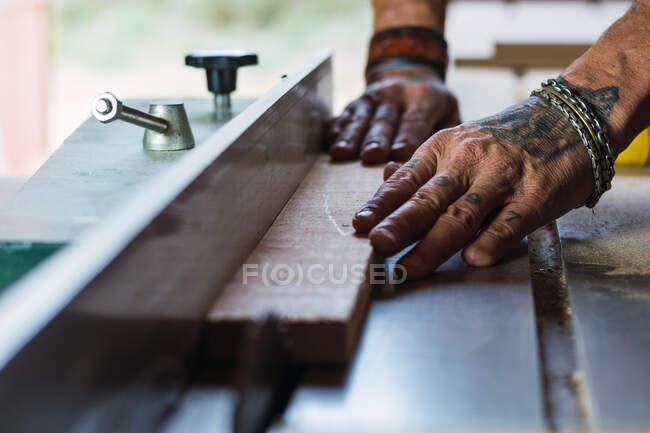 Primer plano de la cosecha macho irreconocible sin un carpintero de pulgar cortar madera con sierra circular en la carpintería — Stock Photo