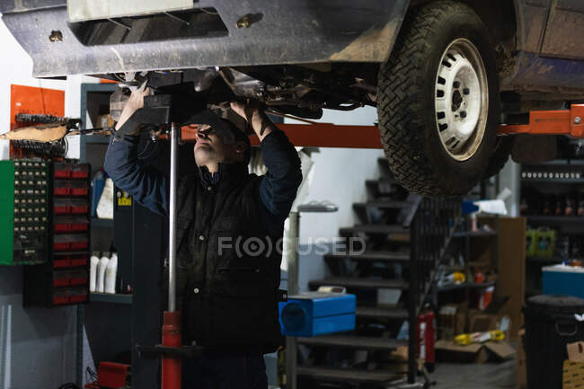 Macho con antorcha automática mientras que la eliminación de tuercas despojadas del coche durante el proceso de reparación en el garaje - foto de stock