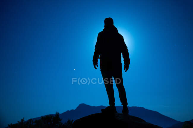 Back view of unrecognizable male tourist admiring colorful sky from mount during trip at sunset — Stock Photo
