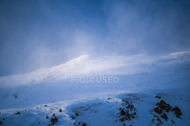 Spettacolare vista del monte grezzo con neve sotto il cielo nebbioso luminoso in inverno alla luce del sole — Foto stock