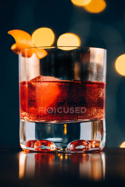 Glas mit erfrischendem alkoholischen Negroni-Cocktail, garniert mit reifen Orangenschalen und inmitten von Barkeeper-Werkzeugen auf den Tisch gestellt — Stockfoto