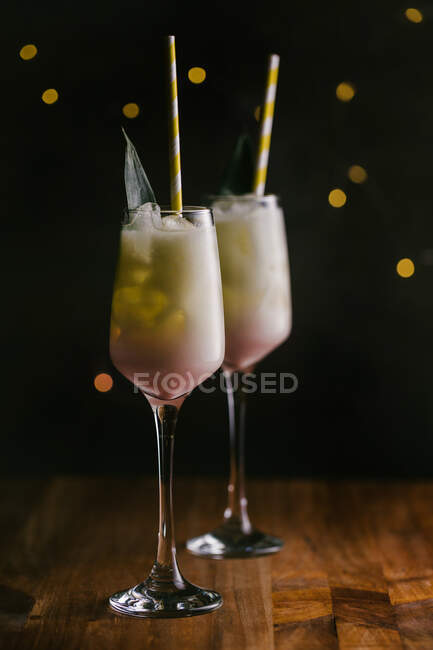 Gläser mit erfrischend süßem Pina Colada Cocktail, garniert mit grünen Blättern, serviert auf einem Holztisch im dunklen Raum — Stockfoto