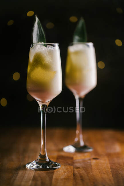 Bicchieri di rinfrescante dolce Pina Colada cocktail guarnito con foglie verdi e servito su tavolo in legno in camera oscura — Foto stock
