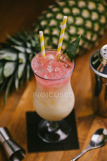 Из выше композиции сладкие классические коктейли Пина Колада подается на барной стойке возле шейкера и jigger — стоковое фото