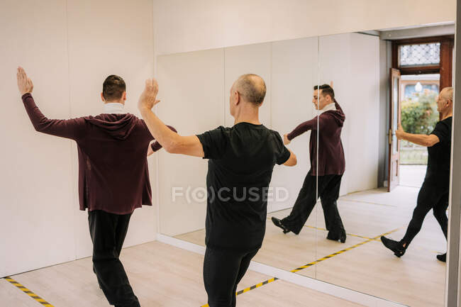 Visão traseira do homem e do instrutor masculino praticando dança de salão no salão com espelho — Fotografia de Stock