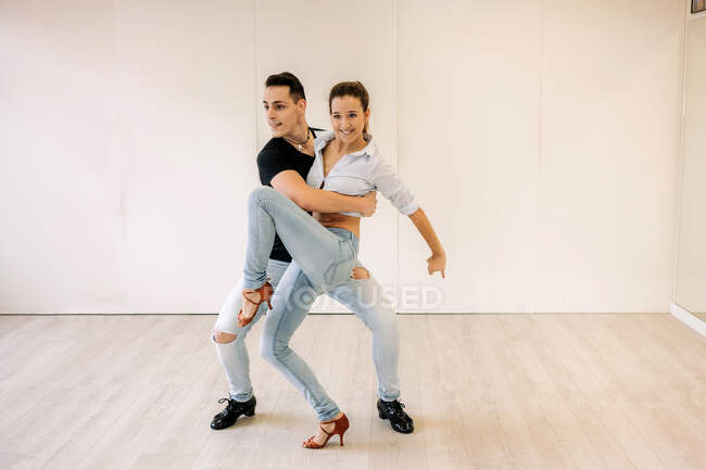 Content skilled couple performing ballroom dance during lesson in bright spacious hall and looking away — Stock Photo