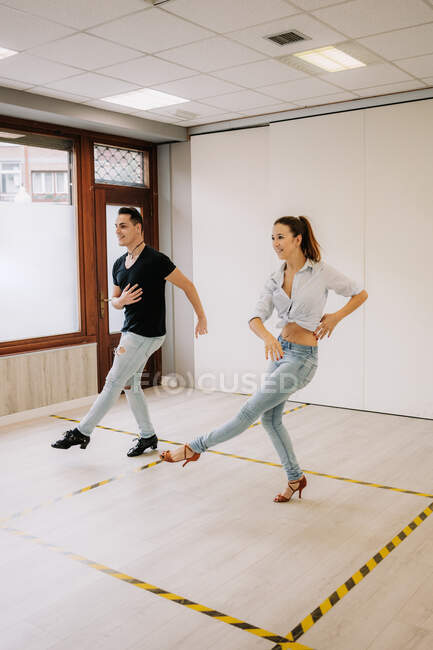 Talentosa pareja realizando bailes de salón mientras ensayan en un amplio y luminoso estudio con espejo durante la clase - foto de stock