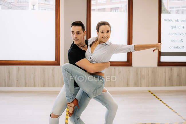 Conteúdo casal qualificado realizando dança de salão durante a aula em salão espaçoso brilhante e olhando para longe — Fotografia de Stock