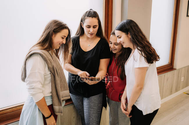 Alto ângulo de jovens bailarinas sorridentes se reunindo no salão e assistindo vídeo de dança no smartphone após lição — Fotografia de Stock