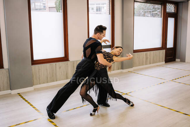 Pareja de bailarines en elegante desgaste realizando bailes de salón  durante la clase en estudio contemporáneo — cuerpo, práctica - Stock Photo  | #459311256