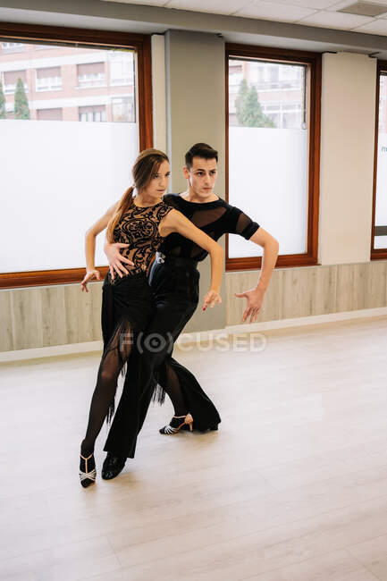 Ein Paar talentierter Tänzer bewegt sich anmutig, während sie im Saal während des Unterrichts Standardtänze einüben — Stockfoto