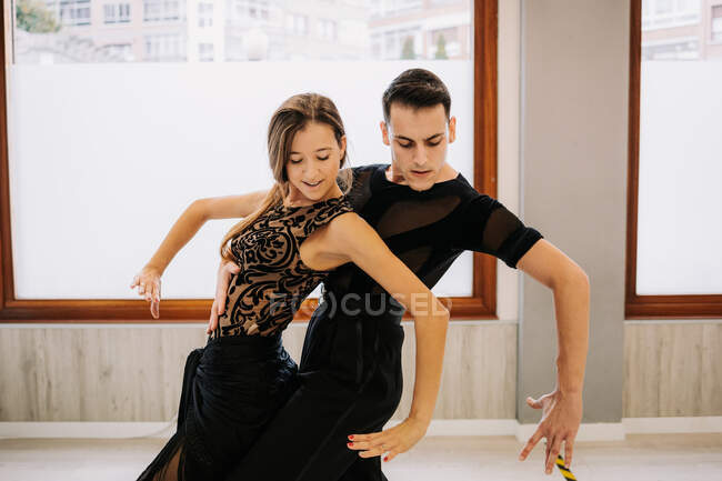 Un par de bailarines talentosos moviéndose con gracia mientras ensayan baile de salón en el salón durante la lección - foto de stock