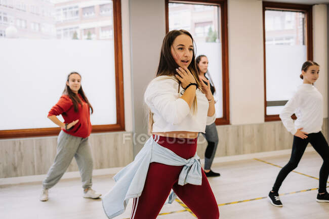 Group of young women and girls rehearsing hip hop dancing movements while practicing in spacious hall together during active lesson with instructor — Stock Photo