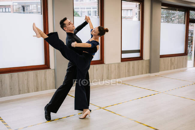 Casal de dançarinos qualificados em roupas elegantes ensaiando movimentos de dança de salão durante a aula em estúdio — Fotografia de Stock