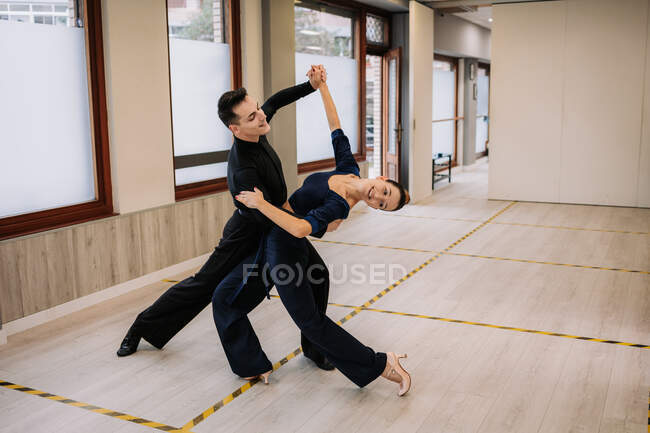 Casal de dançarinos qualificados em roupas elegantes ensaiando movimentos de dança de salão durante a aula em estúdio — Fotografia de Stock