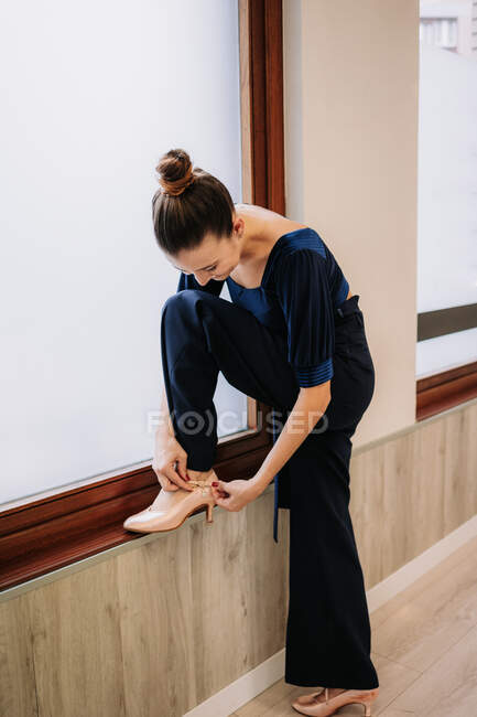 Тонка жінка одягає елегантне взуття для бального танцю перед репетицією в студії — стокове фото
