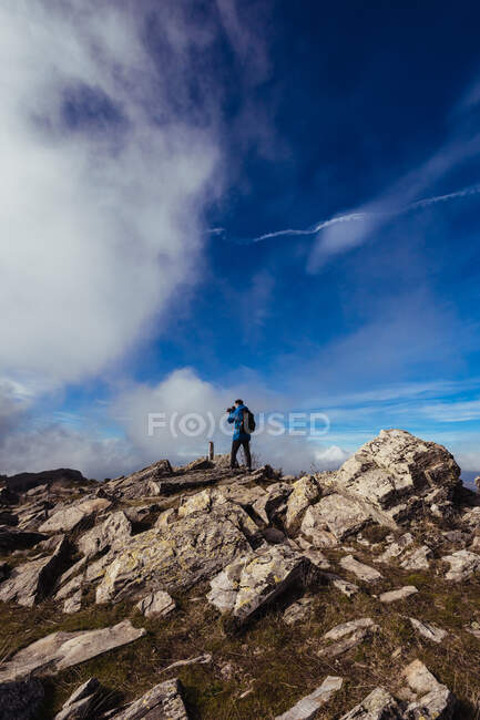 From above back view of anonymous male traveler with backpack taking photo of mount on camera on foggy day — Stock Photo