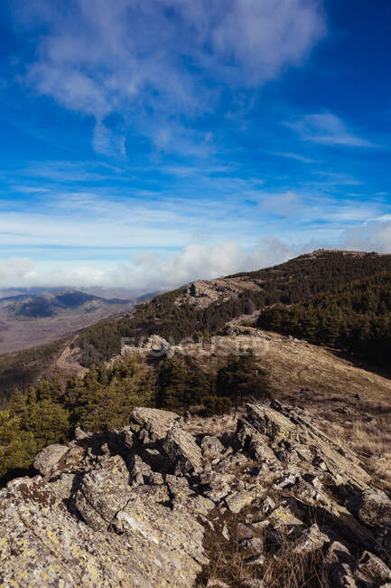 Picturesque view of high ridges with haze under glowing blue sky with clouds in sunlight — Stock Photo