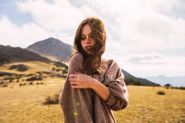 Молода лагідна жінка - мандрівник у повсякденному одязі, що дивиться вниз на гору під сонцем в Іспанії. — стокове фото