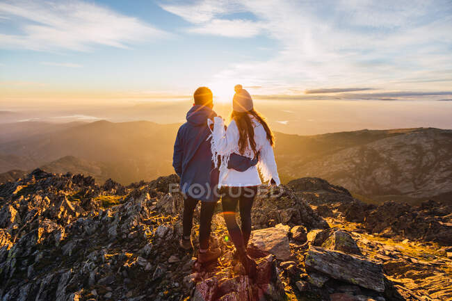 Vue arrière d'un couple anonyme de touristes admirant des montagnes majestueuses sous un ciel brillant au soleil — Photo de stock