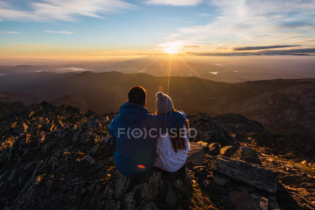 Back view of anonymous couple of tourists admiring majestic mountains under shiny sky in sunlight — Stock Photo