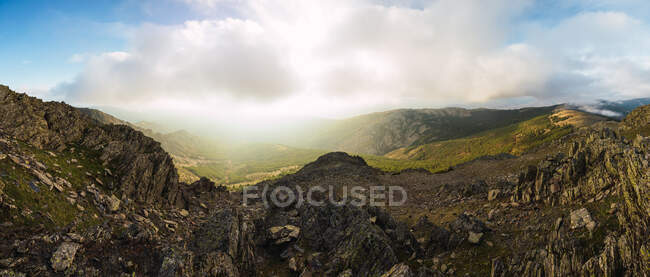 Picturesque panoramic view of high ridges under glowing blue sky with clouds in sunlight — Stock Photo