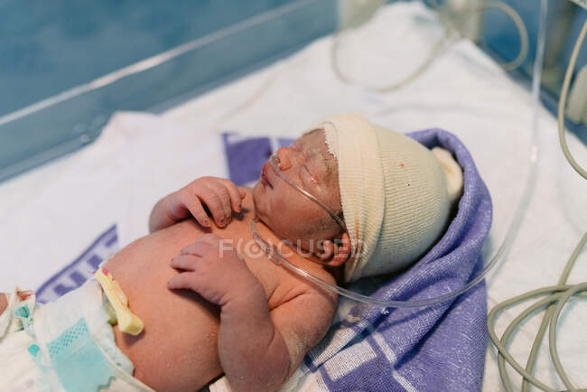 Bebê recém-nascido conectado a um respirador envolto em cobertor após o trabalho de parto no hospital — Fotografia de Stock