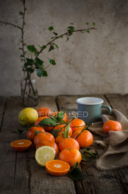 Спелые мандарины и лимон на деревянном столе с чашкой и салфеткой, приготовленными для приготовления мусса — стоковое фото