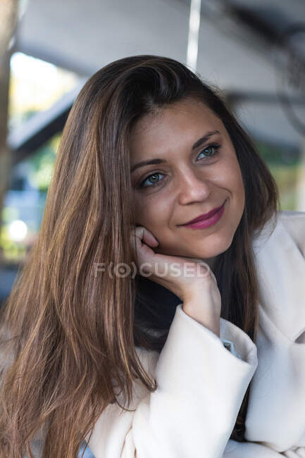 Heureux élégant cheveux longs femme souriant et regardant loin tout en se reposant dans le café — Photo de stock