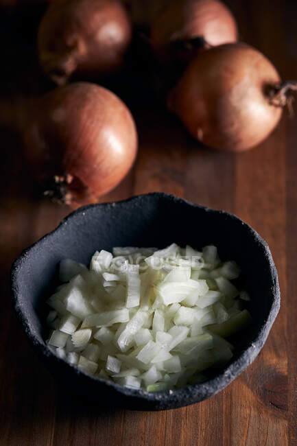 Top view of rustic bowl with pieces of cut onion placed on lumber table in kitchen — Stock Photo