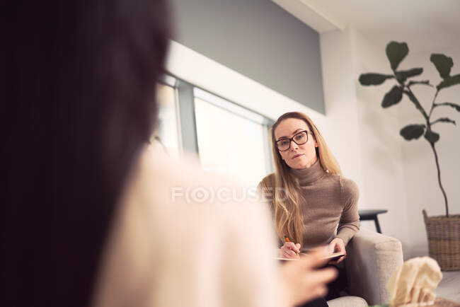 Beraterin sitzt im Sessel und berät unkenntliche Klientin bei Psychotherapietermin — Stockfoto