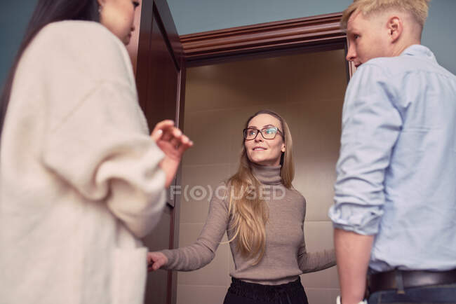Low angle of female psychologist standing in doorway of office during appointment with couple having problems in relationship — Stock Photo