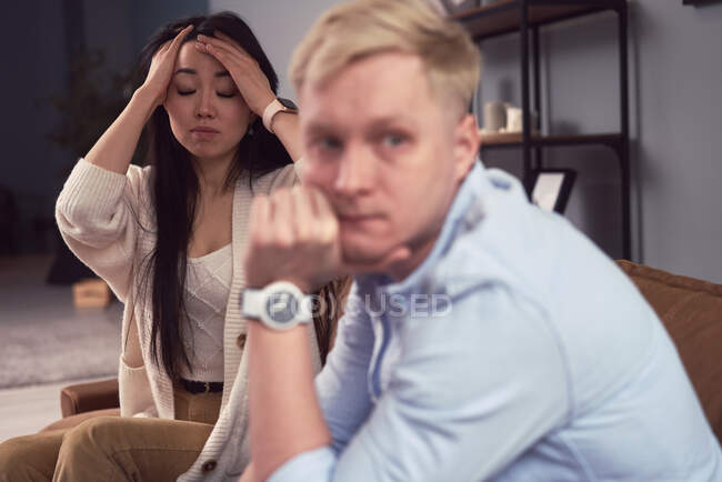 Unhappy Asian woman taking to indifferent man during therapy session in office of psychologist — Stock Photo