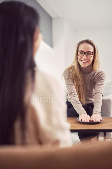 Женщина-психолог с пластиной, жестикулирующей и дающая советы неузнаваемому клиенту во время сеанса психотерапии — стоковое фото