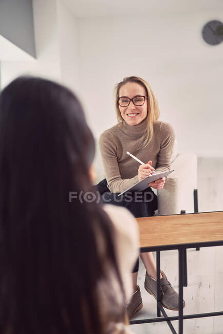 Conselheira feminina alegre ouvindo cliente anônimo enquanto ajuda durante sessão de terapia mental — Fotografia de Stock