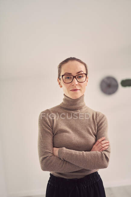 Serious female counselor standing with crossed arms in office for psychotherapy sessions and looking at camera — Stock Photo