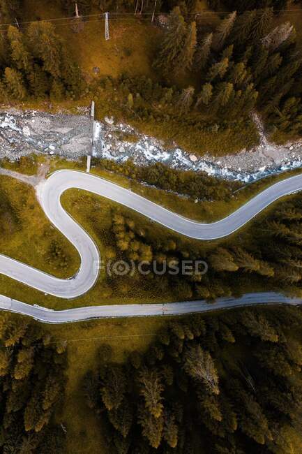 Vue aérienne de la route sinueuse serpentine qui longe le versant montagneux avec des bois de conifères dans les Dolomites en Italie — Photo de stock